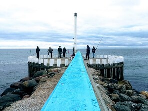 A pier with a blue walkway leading to a lighthouse, surrounded by rocks and the sea. - 4 Star Holiday Home in Hadsund (Hadsund)