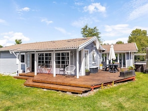 A two-story house with a covered patio, a swing chair, and a barbecue area. - 8 Person Holiday Home in Hadsund (Hadsund)