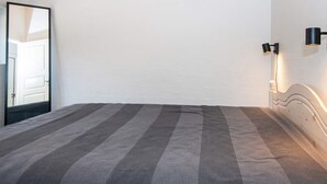 A bedroom with a bed, a mirror, and wall-mounted lighting. - 5 Star Holiday Home in Glesborg (Glesborg)