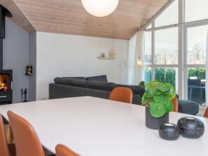 A modern living room with a fireplace, a dining table, and a large window.