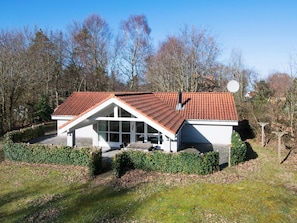 Een modern huis met een schuin dak, grote ramen en een verzorgde tuin.