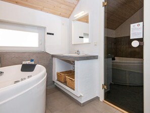 Une salle de bain moderne avec une grande baignoire, un lavabo avec un miroir et une fenêtre au-dessus du lavabo.