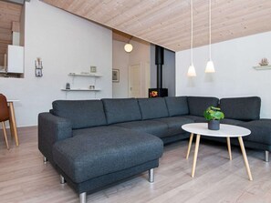 A modern living room with a grey sectional sofa, a round white coffee table, and a small potted plant.
