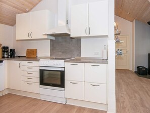 Une cuisine moderne avec des meubles blancs, un four encastré et une cuisinière à gaz.