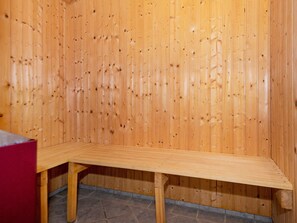 A wooden sauna with a bench and a tiled floor.