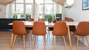 A dining area with a large table, six chairs, and a television. - 5 Star Holiday Home in Glesborg (Glesborg)