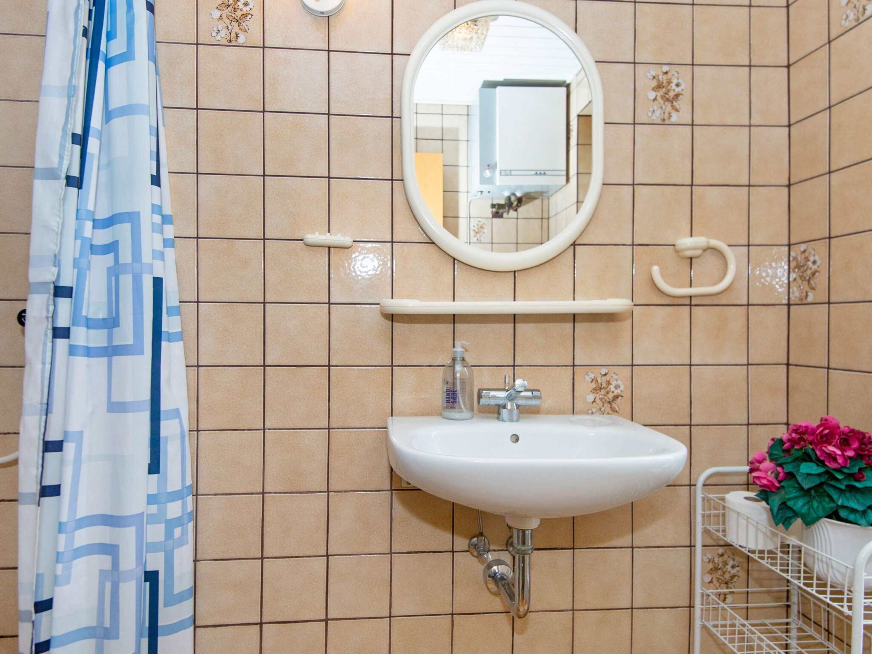 A bathroom with a white sink, a mirror, a towel rack, and a shower curtain.