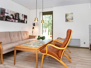 A living room with a sofa, a dining table with chairs, a lamp, and artwork on the walls. - 6 Person Holiday Home in Glesborg (Glesborg)