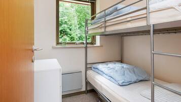 A bunk bed room with a window, a small cabinet, and a radiator.
