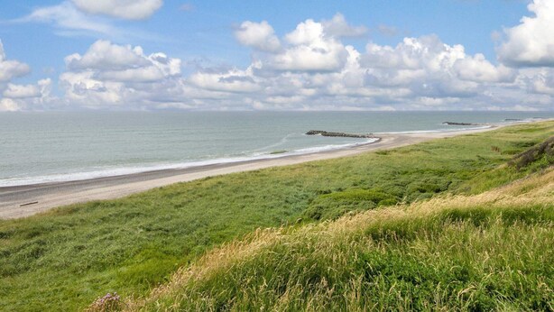 A coastal landscape with a grassy beach area, a rocky outcrop, and a clear sky with clouds. - 12 Person Holiday Home in Lemvig (Lemvig)
