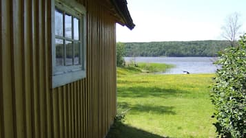 Una cabaña de madera con ventana que da a un lago.