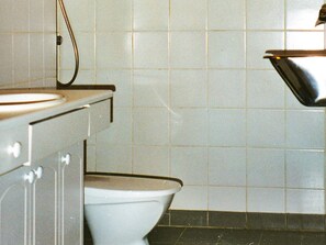 Een badkamer met een wit toilet, een wastafel en een douche.