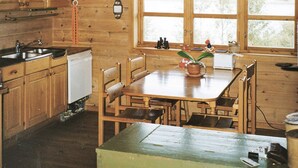 Una cucina in stile baita con tavolo, sedie, finestra con tende e lavello.