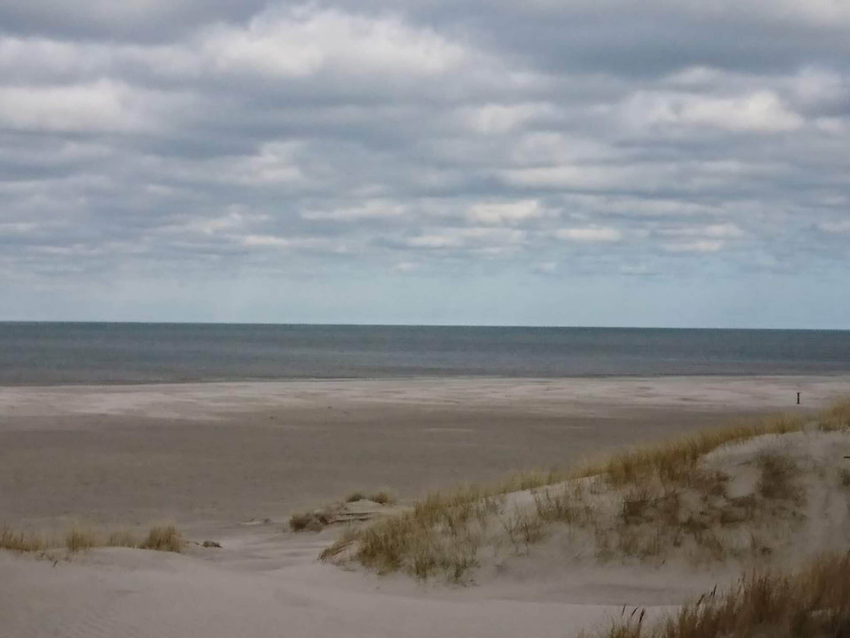 A beach with sand dunes and a cloudy sky.