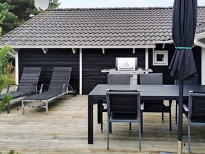 An outdoor patio with a table and chairs, a grill, and a covered seating area. - 4 Star Holiday Home in Lokken (Lokken)