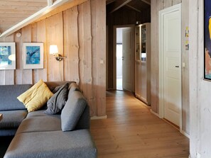 A wooden interior with a sofa, a wall-mounted light, and a door leading to another room. - 4 Star Holiday Home in Lokken (Lokken)