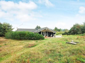 A house with a covered porch, a satellite dish, and a grill outside.