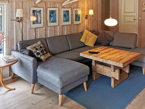 A modern living room with a sectional sofa, a wooden coffee table, and a blue rug.