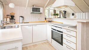 A modern kitchen with white cabinetry, a microwave, a stove, and a sink. - 8 Person Holiday Home in Otterup (Otterup)