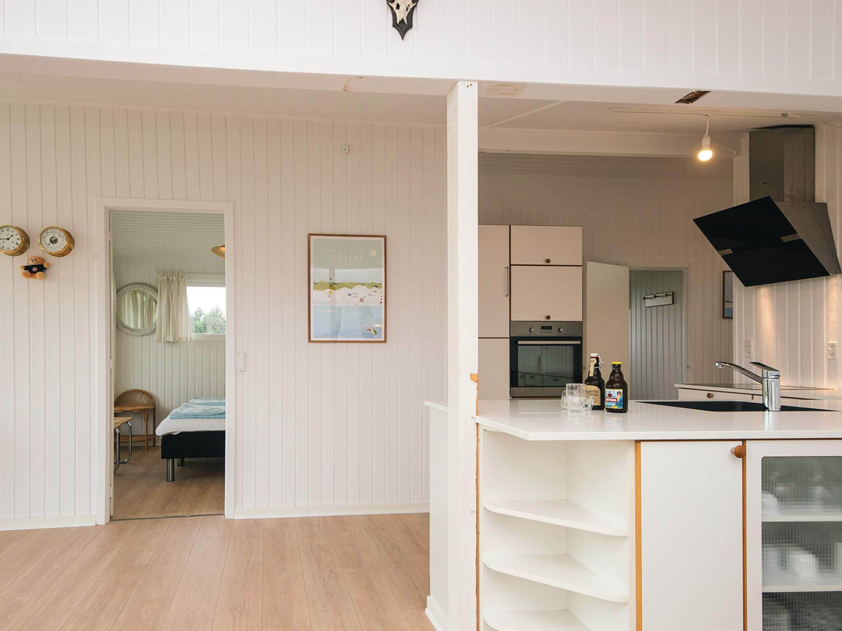 A modern kitchen with white cabinetry, a built-in oven, and a hanging light fixture.