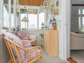 A cozy room with a wicker chair, a wooden cabinet, and a window with a view.