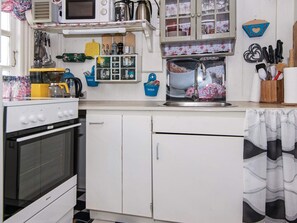 A kitchen with a stove, microwave, and various utensils.