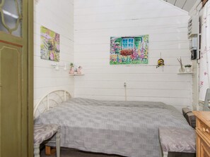 A bedroom with a bed, a window with a floral painting, and a small shelf with decorative items. - Vintage Holiday Home in Rømø near Beach (Rømø)
