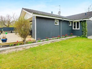 A modern two-story house with a dark grey exterior, a satellite dish, and a small garden with red tulips.