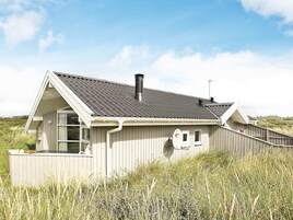 Una casa costera con techo inclinado, chimenea y antena parabólica.