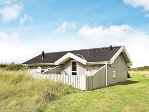 En enplansbyggnad med ett sluttande tak, en liten veranda och ett inhägnat område.