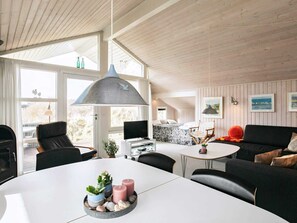 A modern interior with a dining table, chairs, a sofa, a TV, and artwork on the walls.