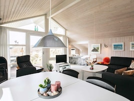 A modern interior with a dining table, chairs, a sofa, a TV, and artwork on the walls.