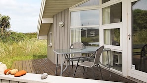 Eine Terrasse mit einem Glastisch und Stühlen mit Blick auf eine grüne Wiese.