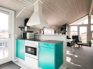 Una cocina moderna con una isla central, armarios blancos y un amplio ventanal.