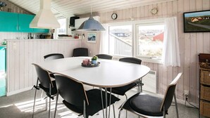 A dining area with a white table, black chairs, a pendant light, and a view of the outdoors through large windows. - Spacious Holiday Home Nearby the National Park Loonse en Drunese Duinen (Hjørring)