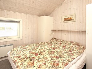A bedroom with a bed, a window, a wall-mounted shelf with a picture, and a wall heater. - Spacious Holiday Home Nearby the National Park Loonse en Drunese Duinen (Hjørring)