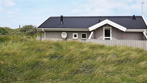 Eingeschossiges Haus mit dunklem Dach, Schornstein und Satellitenschüssel.