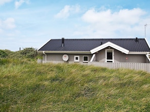 Ett envåningshus med ett mörkt tak, en skorsten och en satellantenn.