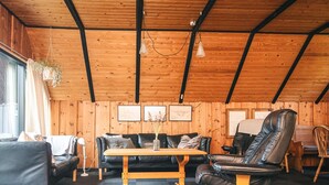 A cozy room with a wooden ceiling, a black leather sofa, a wooden coffee table, and a leather recliner. - 6 Person Holiday Home in Blavand (Blavand)