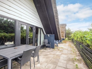 An outdoor patio with a table and chairs, a covered seating area, and a stone pathway.