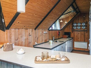 A kitchen with wooden walls, a central island, and a ceiling with exposed beams. - 6 Person Holiday Home in Blavand (Blavand)