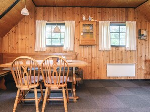 A wooden interior with a dining table, chairs, a bench, two windows with curtains, a cabinet, and a radiator. - 6 Person Holiday Home in Blavand (Blavand)