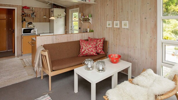 A cozy living room with a brown sofa, a white coffee table, and a window with a view of greenery. - 4 Person Holiday Home in Hojslev (Hojslev)