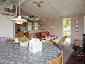 A cozy room with a round table, a sofa, and a chair. There is a window with a view of greenery outside. - 4 Person Holiday Home in Hojslev (Hojslev)