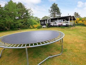 A trampoline in a grassy yard with a house in the background. - 4 Person Holiday Home in Hojslev (Hojslev)