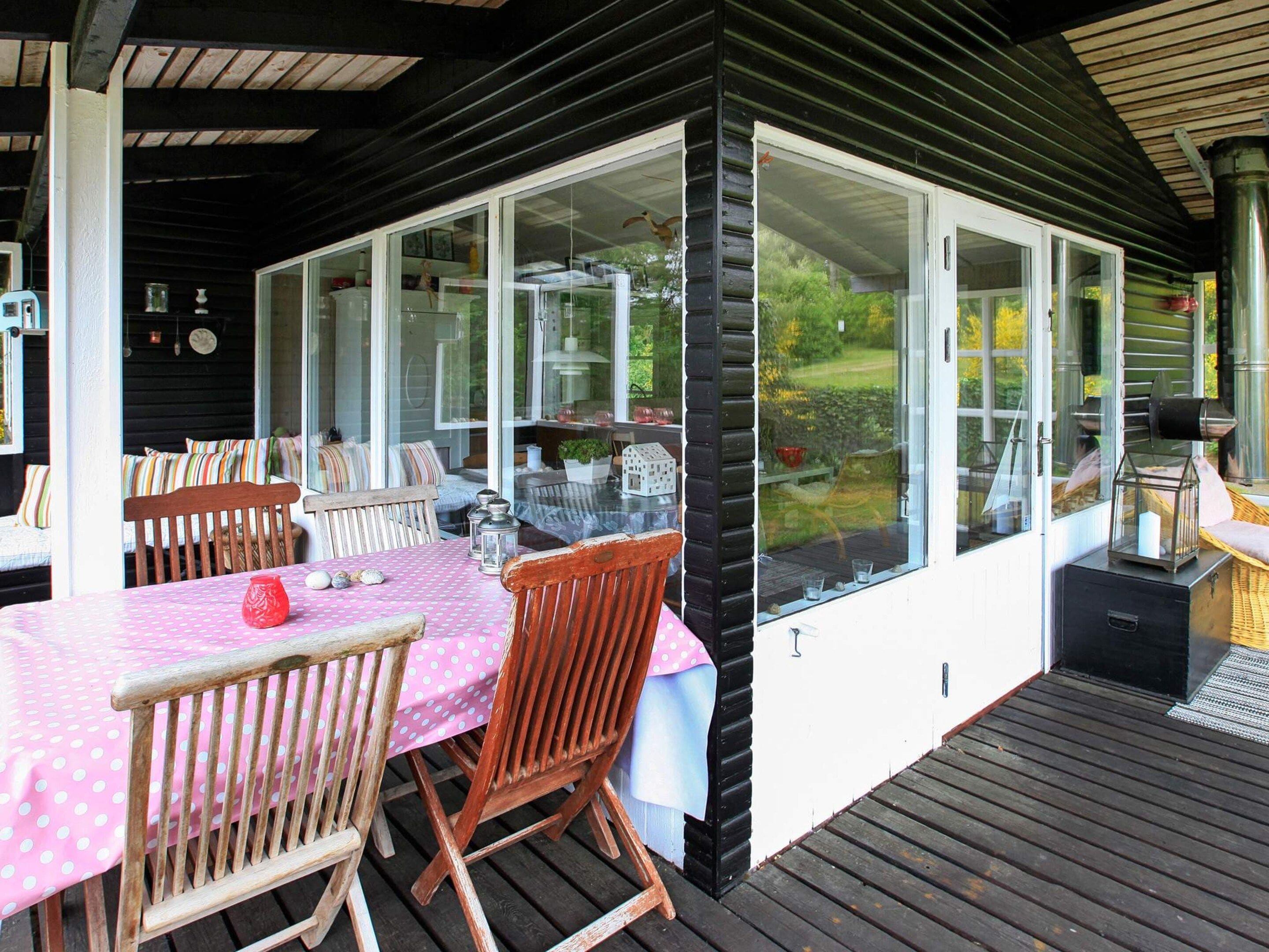 An outdoor dining area with a table and chairs, a covered patio, and a view of the garden.