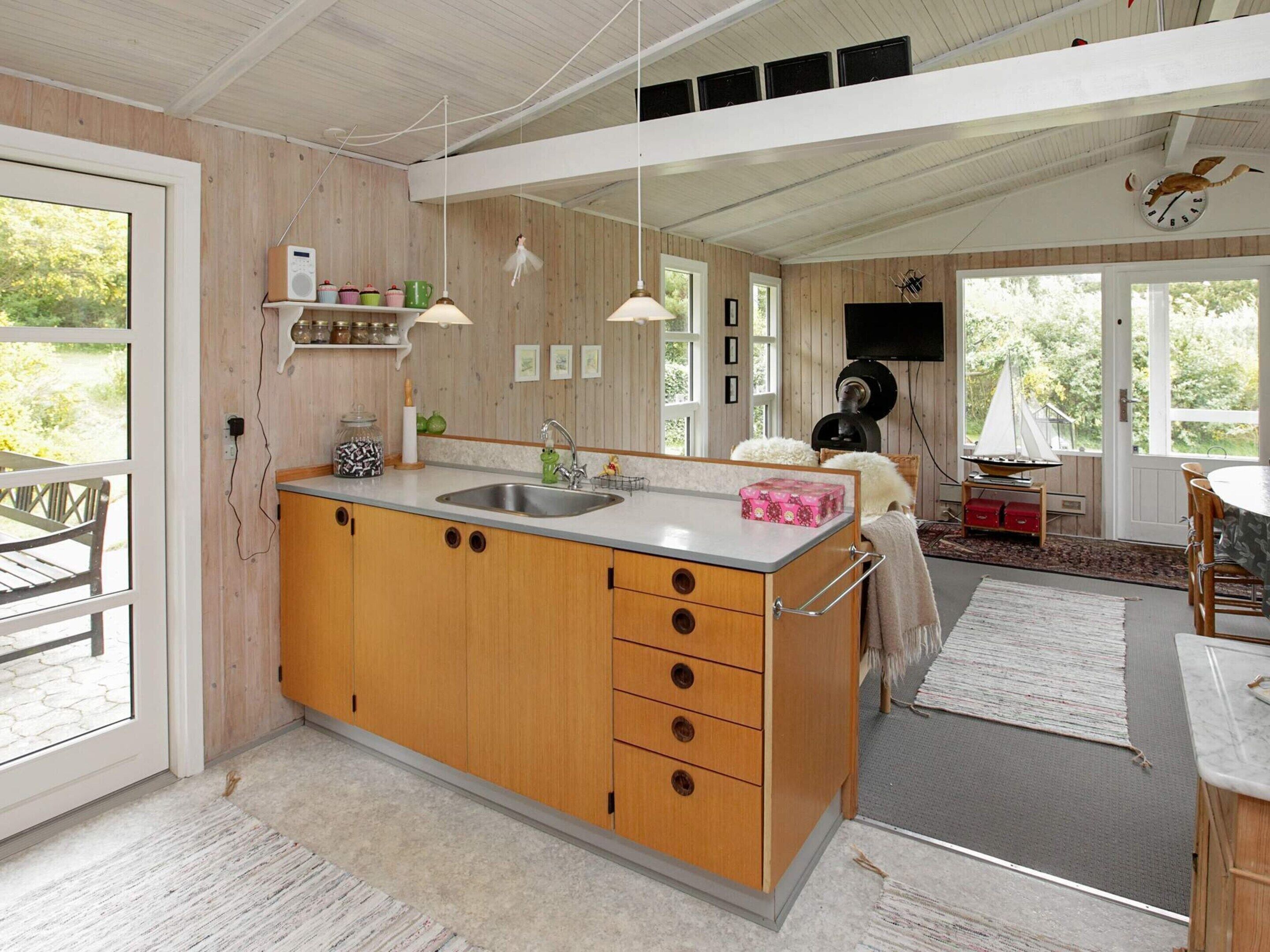 A modern kitchen with wooden cabinets, a sink, and a dining area with a sailboat model.