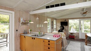 A modern kitchen with wooden cabinets, a sink, and a dining area with a sailboat model. - 4 Person Holiday Home in Hojslev (Hojslev)