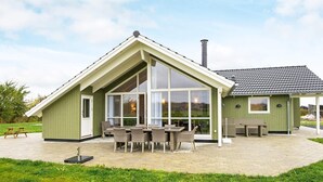 A green-roofed building with large windows and a patio area with wicker furniture. - Splendid Holiday Home in Jutland With Whirlpool (Sydals)