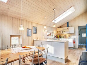 A modern kitchen with wooden walls, a central island, and pendant lighting. - 5 Star Holiday Home in Nexo (Akirkeby)